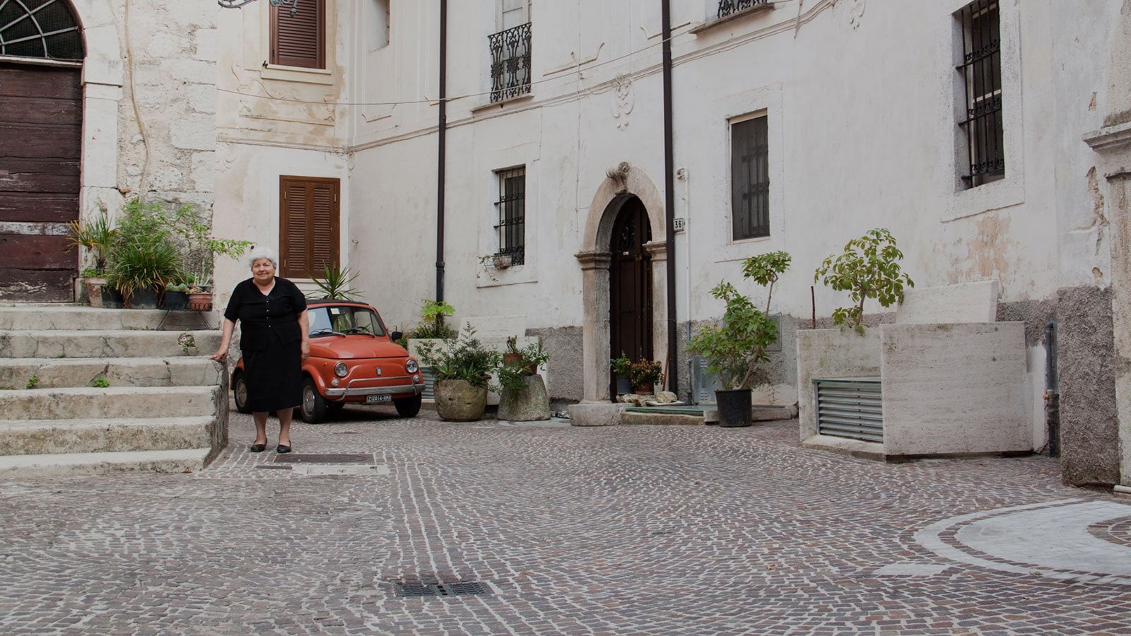Everyday life in our medieval village: old Italian woman and original Fiat 500 - Italian food and wine stay